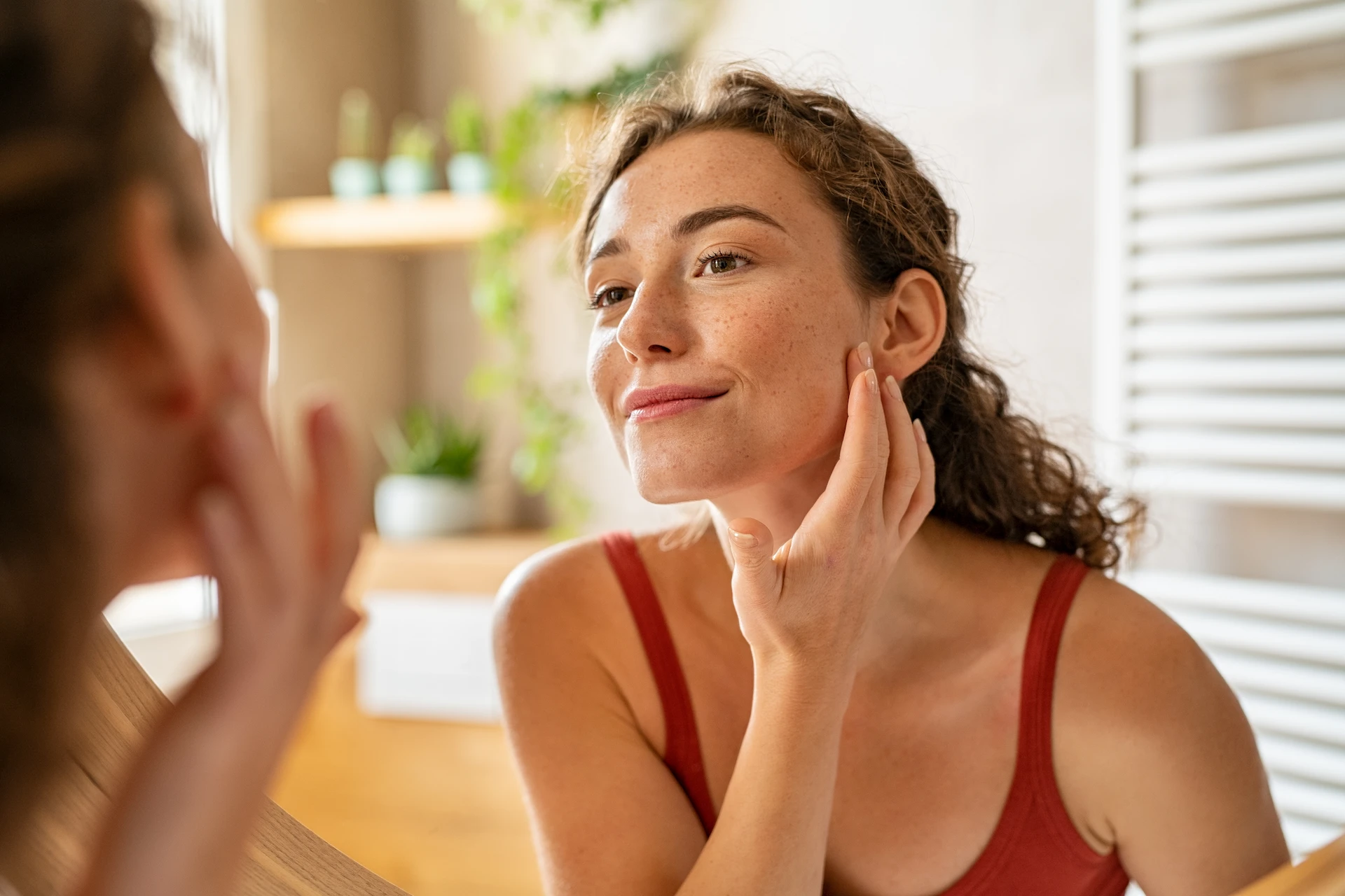 woman inspecting her skin in a mirror