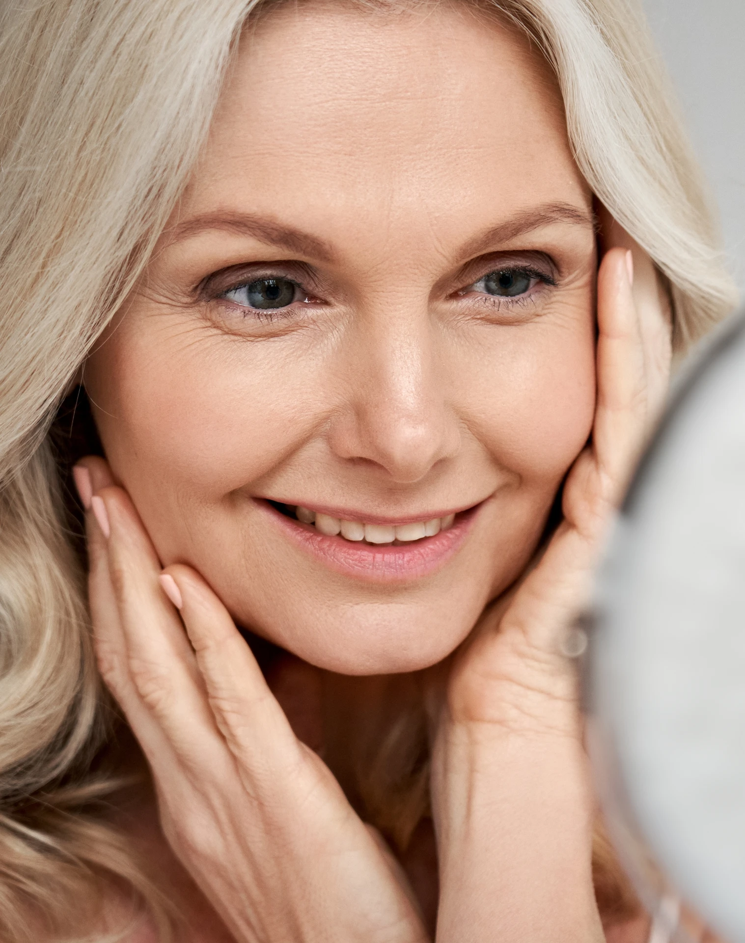 woman smiling whilst looking into a mirror